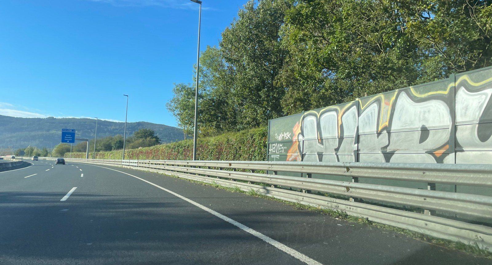Paneles acústicos convencionales cubiertos de grafitis junto a una vía